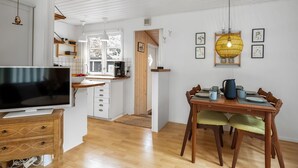 A modern kitchen with white cabinetry, a dining area with wooden furniture, and a television on a wooden stand. - "Gia" - 1.3km from the sea by Interhome (Hals)