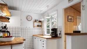 A kitchen with white cabinets, a wooden countertop, a coffee maker, and a clock on the wall. - "Gia" - 1.3km from the sea by Interhome (Hals)