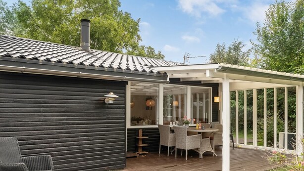 A wooden deck with outdoor furniture, a covered patio area, and a building with a tiled roof. - "Gia" - 1.3km from the sea by Interhome (Hals)