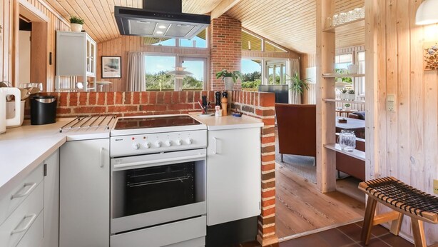 Eine moderne Küche mit Backofen, Herd und einem großen Fenster mit Blick ins Freie.