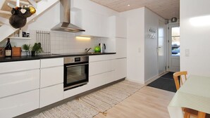 Et moderne køkken med hvide skabe, indbygget ovn og en trætrap.