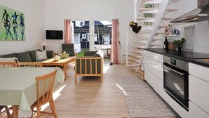 Et moderne køkken med hvide skabe, en sort bordplade og et emfang i rustfrit stål.