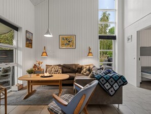A modern living room with a sofa, armchairs, a coffee table, and artwork on the walls.