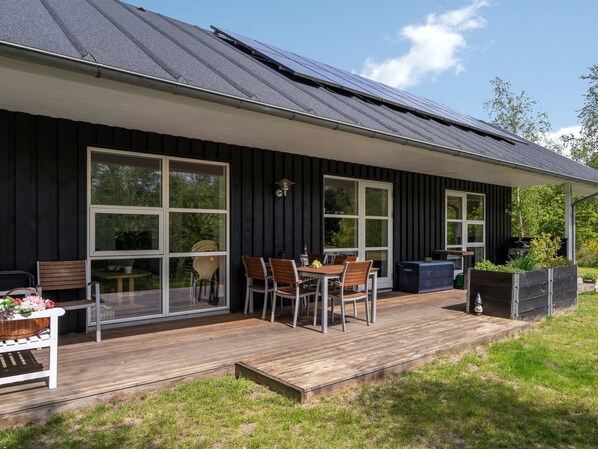 Una casa moderna con terraza, ventanas amplias y paneles solares en el techo.