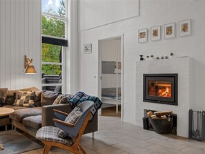 A modern living room with a fireplace, a sofa, a chair, and a dining area.