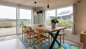 A dining area with a wooden table and chairs, a vase with flowers, and a view of the outdoors.
