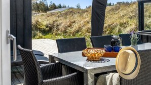 An outdoor dining area with wicker chairs and a table, a hat, and a basket. - "Ingela" - 350m from the sea by Interhome (Løkken)