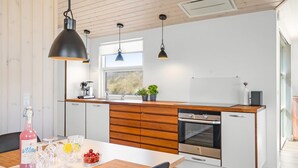 A modern kitchen with wooden cabinets, a built-in oven, and pendant lighting. - "Ingela" - 350m from the sea by Interhome (Løkken)