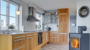 Eine moderne Küche mit Holzausbau, einem Backofen, einem Herd und einem großen Fenster für natürliches Licht.
