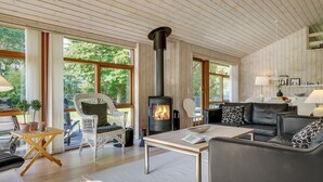 A cozy living room with a fireplace, large windows, and comfortable seating.