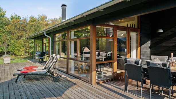 A wooden deck with outdoor furniture, a covered seating area, and a visible chimney.