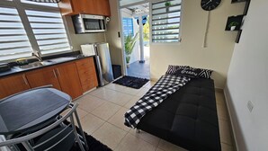 Un espacio habitable compacto con kitchenette, sofá cama y comedor.