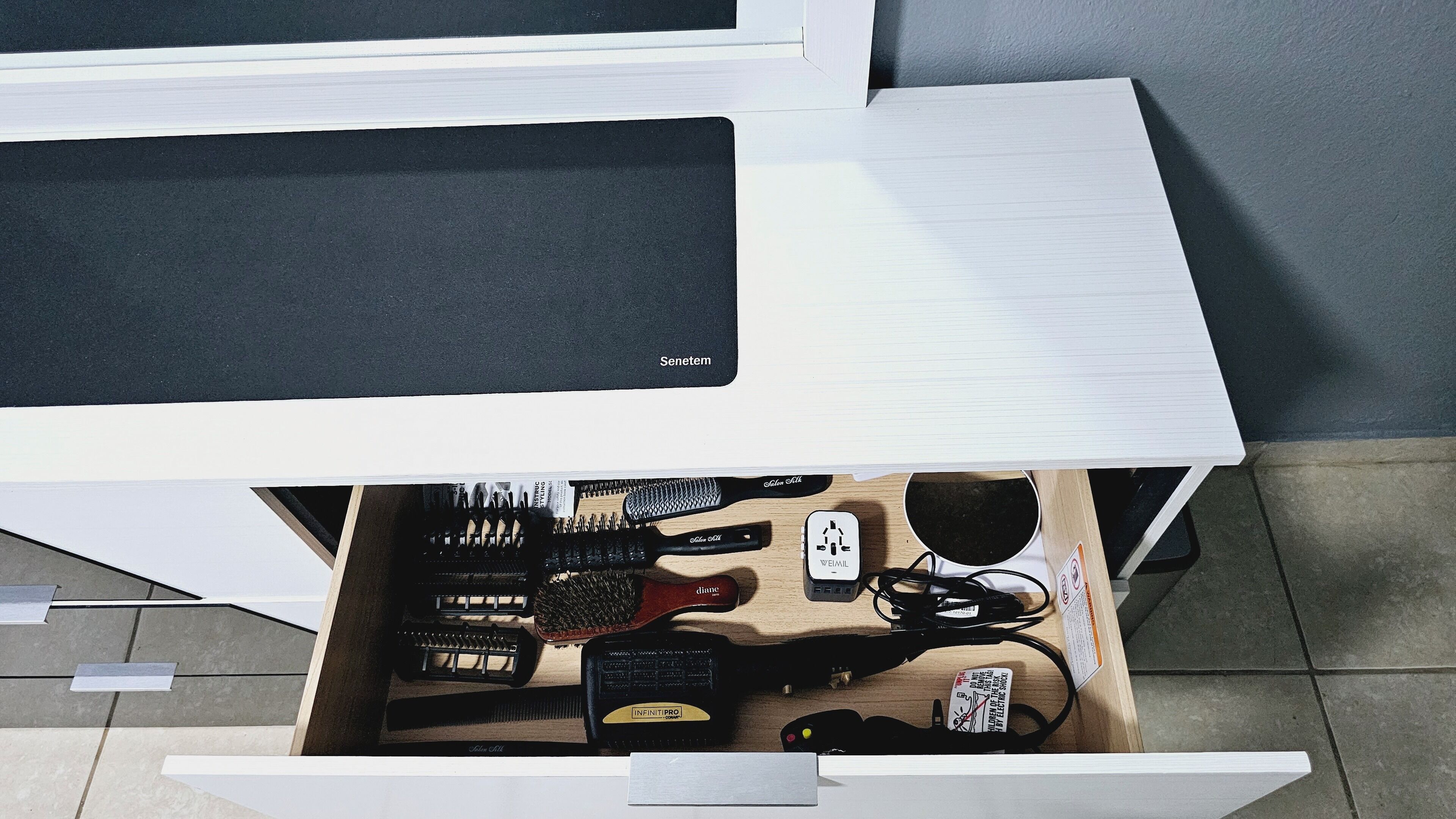 A drawer with various hair care products including brushes, combs, and hair care accessories.