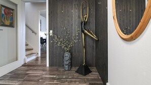 Un intérieur moderne avec un plancher en bois, une sculpture noire et dorée et un grand miroir.