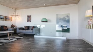Un salon moderne avec un canapé, une vitrine et des œuvres d’art accrochées aux murs.