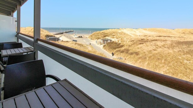 Un balcon avec vue sur la plage et les dunes.
