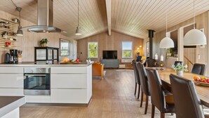 A modern kitchen with a central island, a dining area with a wooden table and chairs, and a living space with a TV and seating. - "Gerhild" - 300m from the sea by Interhome (Ebeltoft)