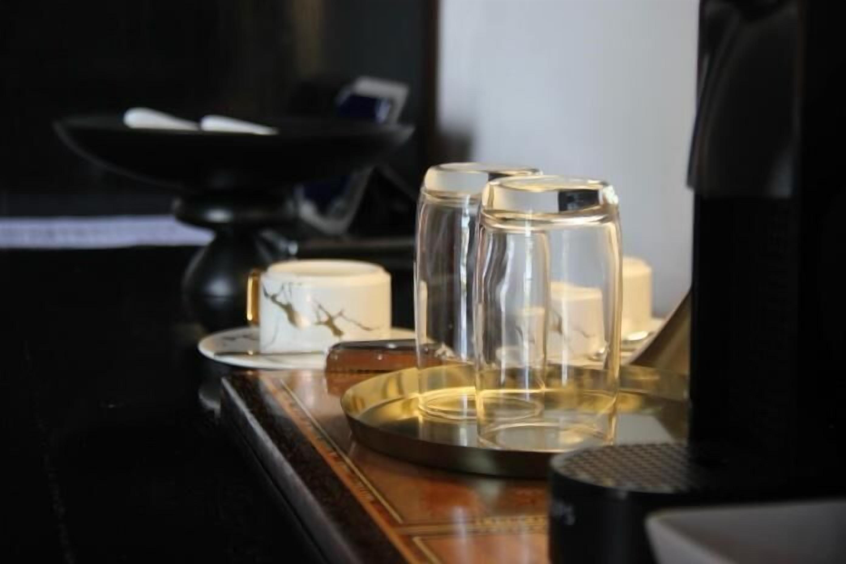 Una bandeja con vasos transparentes y una vela sobre una superficie de madera pulida.