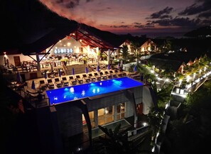 Un resort con piscina, zona de estar al aire libre y montañas al fondo.