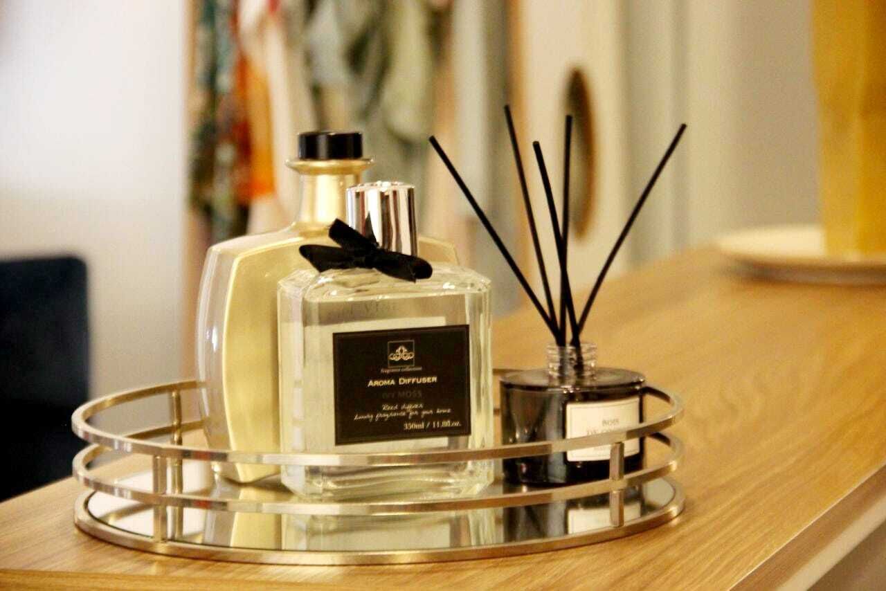 A bottle of perfume on a tray with black candle wicks.