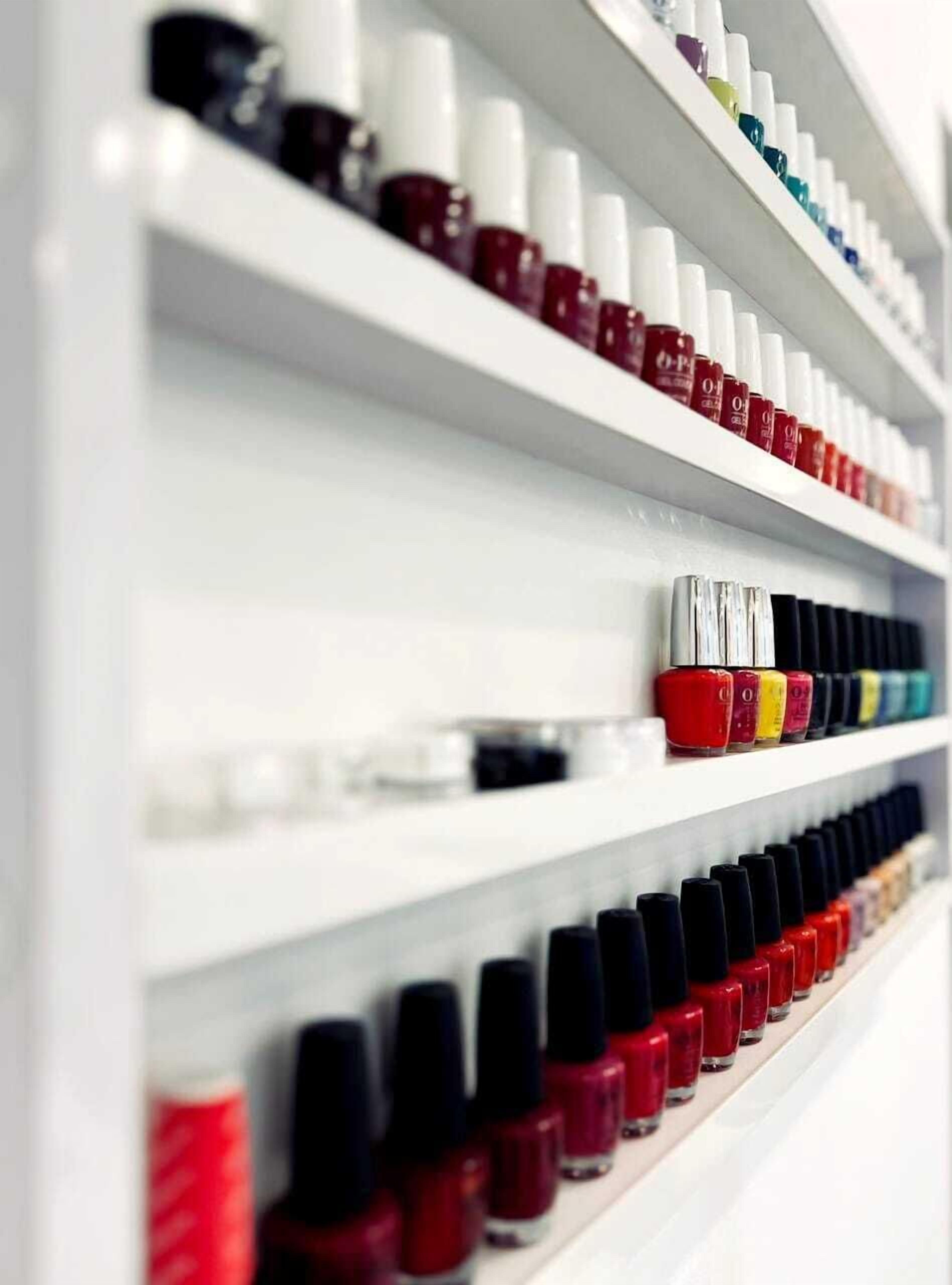Uma parede com várias embalagens de esmalte organizadas, em diversas cores.