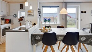 Een moderne keuken met een centraal eiland, witte kasten en hanglampen.