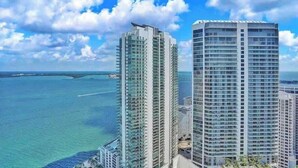 Dois edifícios altos com vista para o oceano e um céu parcialmente nublado.