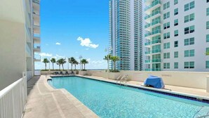 Piscina com vista para edifícios altos e palmeiras.