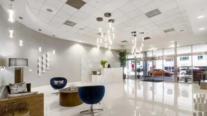 Um lobby moderno com balcão de recepção, área de estar e entrada de vidro.