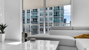 Una sala de estar moderna con un sofá blanco, una mesa de centro de vidrio y una planta en maceta.