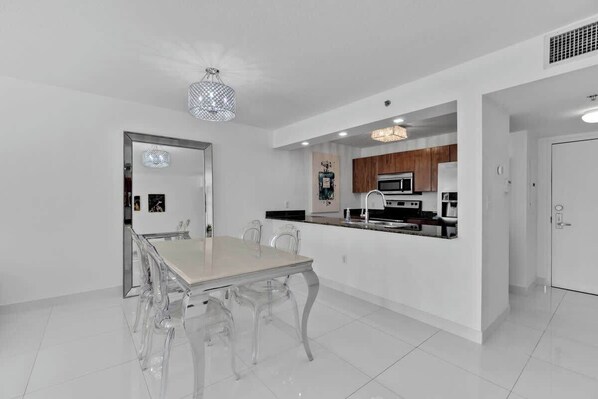 A modern kitchen with white cabinetry, a central island, and stainless steel appliances.