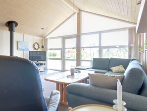 Ein modernes Wohnzimmer mit großem Fenster, Fernseher, Sofa und Couchtisch.