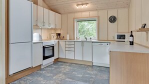 Een moderne keuken met witte kasten, een inbouwoven, een magnetron en een raam met uitzicht op groen.