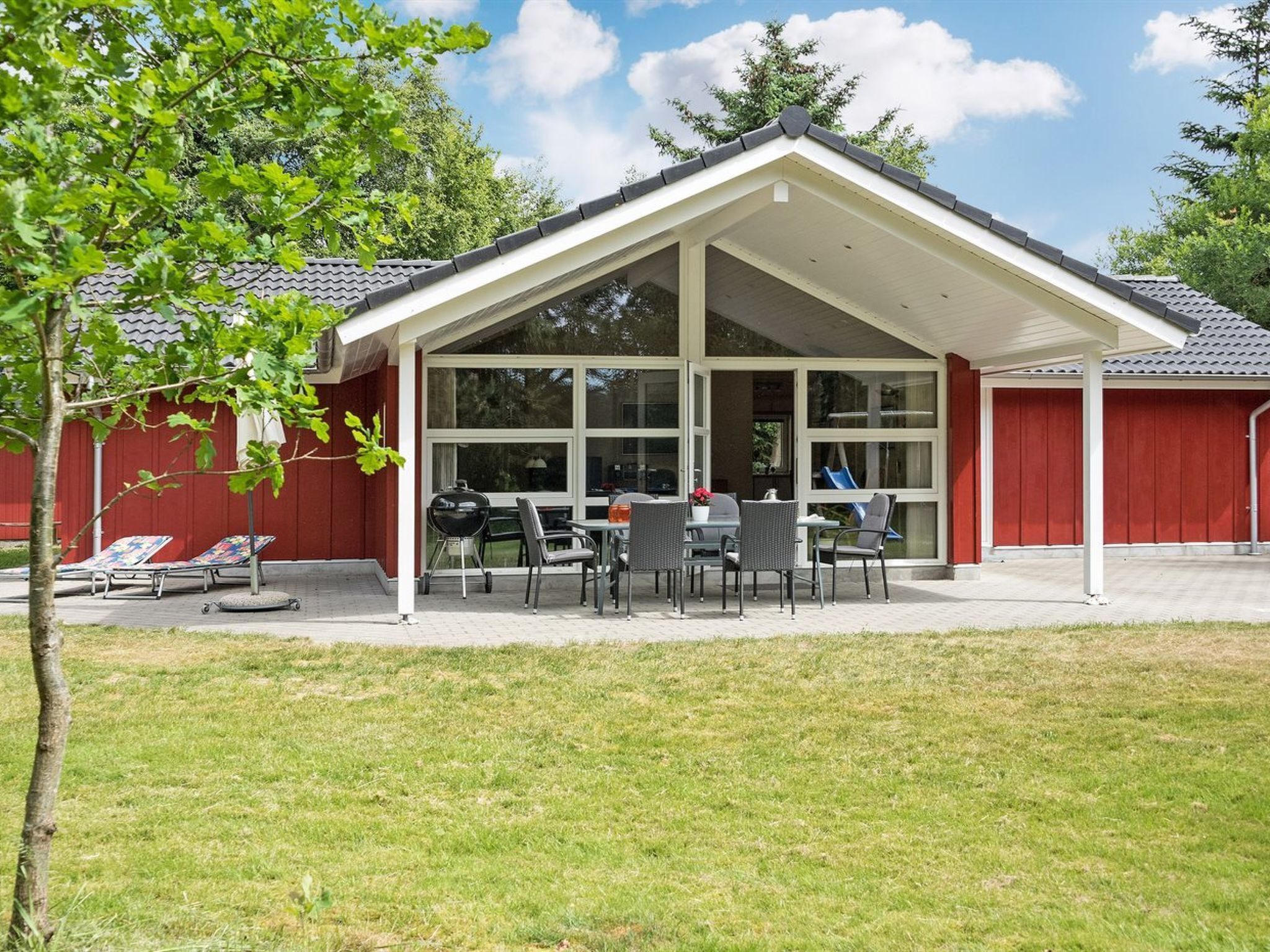 A covered patio area with a grill and outdoor seating.