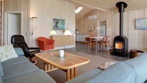 Een gezellige woonkamer met een bank, een eettafel en een open haard.