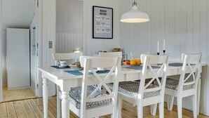Et spiseområde med et hvidt bord og stole, en hængende lampe og et indrammet citat på væggen.