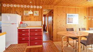 Ein Holzblockhaus-Interieur mit Küche, Essbereich und einem Flur.