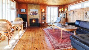 Ein gemütliches Wohnzimmer mit Kamin, Holzböden, einer Couch, einem Tisch und einem Fernseher.