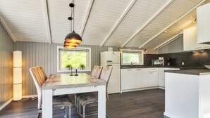 A modern kitchen with white cabinetry, a central island, and a pendant light above the dining table.
