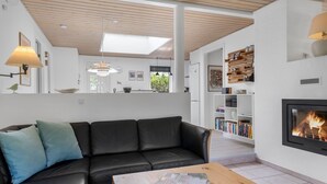Un salon moderne avec un canapé en cuir noir, une table basse en bois et une cheminée.