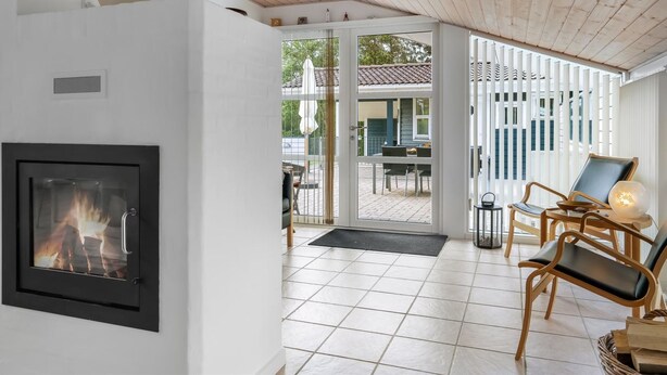 Un intérieur moderne avec une cheminée, un coin repas et une vue sur une terrasse extérieure, accessible par une porte vitrée.