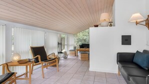 Un vaste espace de vie doté d’un plancher en bois, d’un canapé noir, de chaises en bois et d’une table à manger.