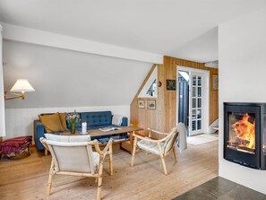 A cozy living room with a blue sofa, wooden chairs, a coffee table, and a fireplace.