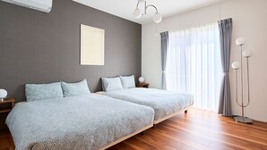 Un dormitori modern amb dos llits, una finestra gran amb cortines, una làmpada al sostre i aire condicionat fixat a la paret.