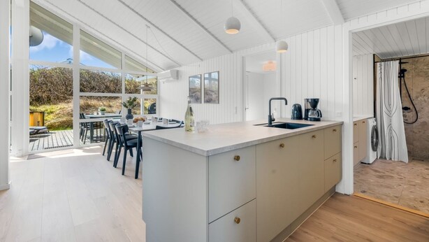 A modern kitchen with a large island, a dining area with outdoor seating, and a view of the outdoors. - "Midja" - 800m from the sea by Interhome (Hvide Sande)