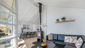 A modern living room with a black sofa, a round coffee table with fruit, and a fireplace. - "Midja" - 800m from the sea by Interhome (Hvide Sande)