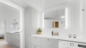 A modern kitchen with white cabinetry, a built-in washing machine, and a large mirror above the counter. - "Midja" - 800m from the sea by Interhome (Hvide Sande)