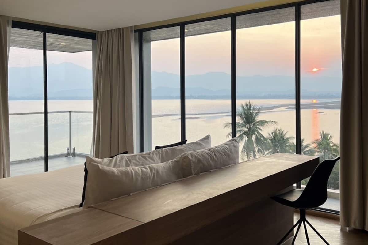 Una habitación de hotel moderna con un amplio ventanal que ofrece vistas al mar y a las montañas.