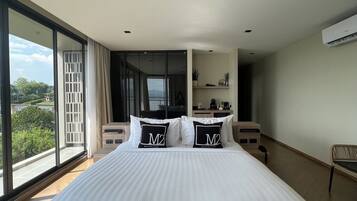 A modern bedroom with a large bed, a view of the outdoors, and a built-in desk area.