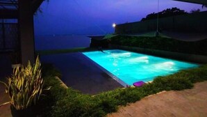 Una piscina al aire libre con vistas al mar al atardecer.